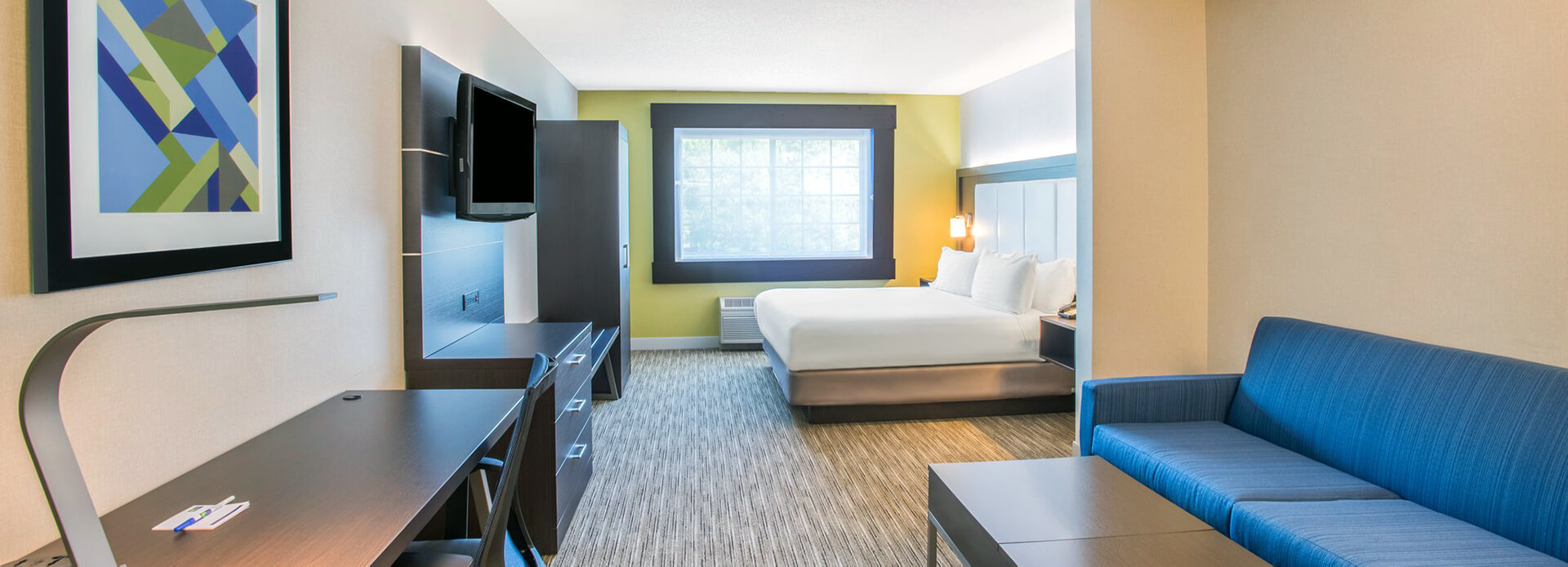Hotel room with lounge in foreground and bedroom in background.