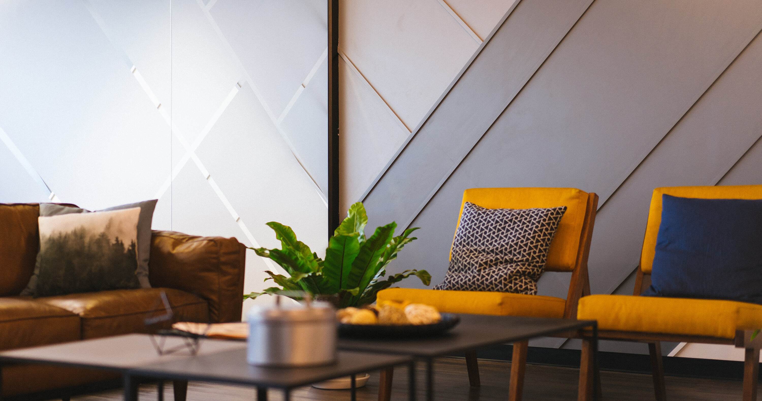 Cozy seating area in hotel lounge with leather couch and bright orange chairs.